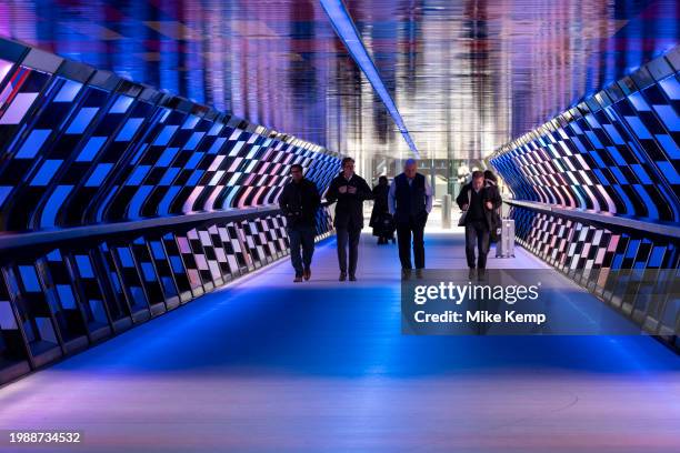 People interacting with the geometric public contemporary artwork 'Captivated by Colour' by artist Camille Walala in the tunnel walkway at Adams...