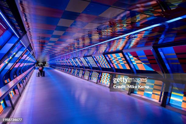 People interacting with the geometric public contemporary artwork 'Captivated by Colour' by artist Camille Walala in the tunnel walkway at Adams...