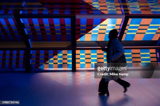 People interacting with the geometric public contemporary artwork 'Captivated by Colour' by artist Camille Walala in the tunnel walkway at Adams...