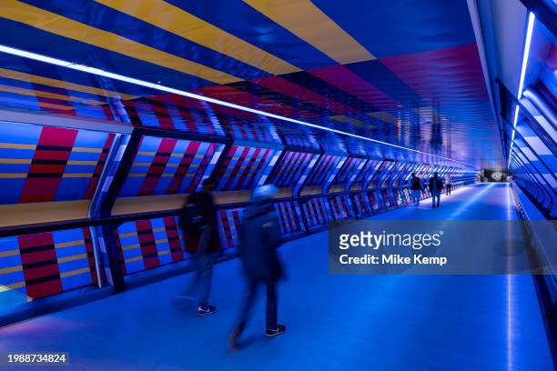 People interacting with the geometric public contemporary artwork 'Captivated by Colour' by artist Camille Walala in the tunnel walkway at Adams...
