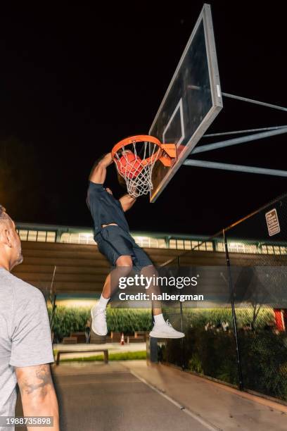 man hanging by the rim and dunking the basketball - shooting baskets stock pictures, royalty-free photos & images