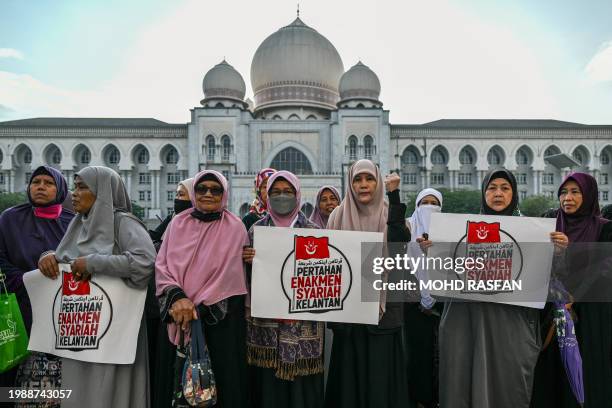 Members of the Pan-Malaysian Islamic Party display placards reading "Maintain the Kelantan Sharia Enforcement" outside the Palace of Justice in...