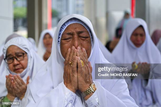 Members of the Pan-Malaysian Islamic Party recite prayers, as they await the Federal Court's decision on Kelantan state's sharia law criminal...