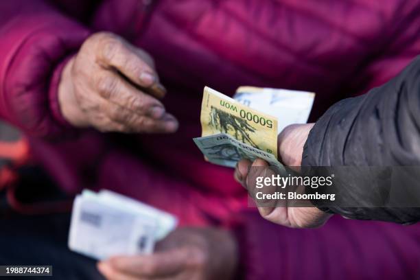 Customer pays his purchase at the Moraenae Market ahead of Lunar New Year in Jeonju, Jeollabuk Province, South Korea, on Thursday, Feb. 8, 2024....