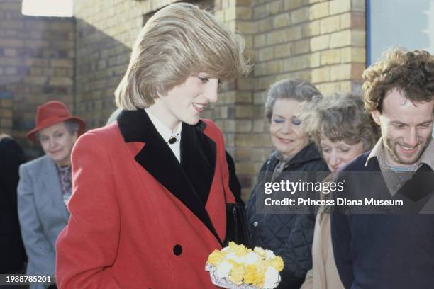 Diana, Princess of Wales , wearing a Catherine Walker coat, holds flowers as she visits the Charlie Chaplin Adventure Playground for handicapped...
