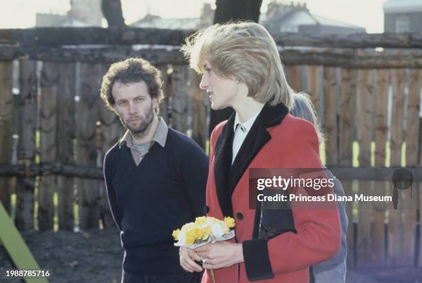 Diana, Princess of Wales , wearing a Catherine Walker coat, holds flowers as she visits the Charlie Chaplin Adventure Playground for handicapped...