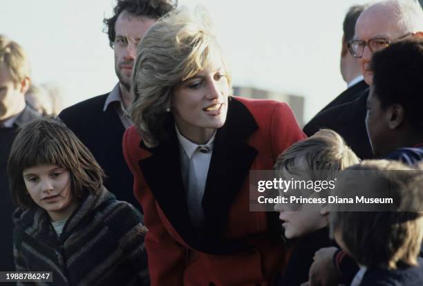 Diana, Princess of Wales , wearing a Catherine Walker coat, is surrounded by children at the Charlie Chaplin Adventure Playground for handicapped...