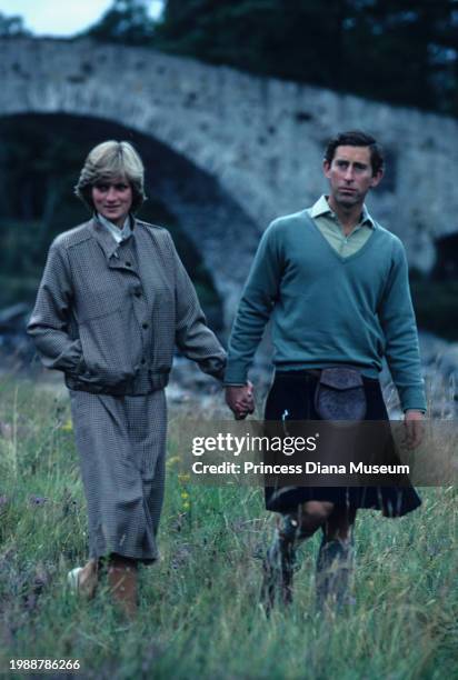 Diana, Princess of Wales , wearing a suit designed by Bill Pashley, and husband Charles III of the United Kingdom walk along the banks of the river...