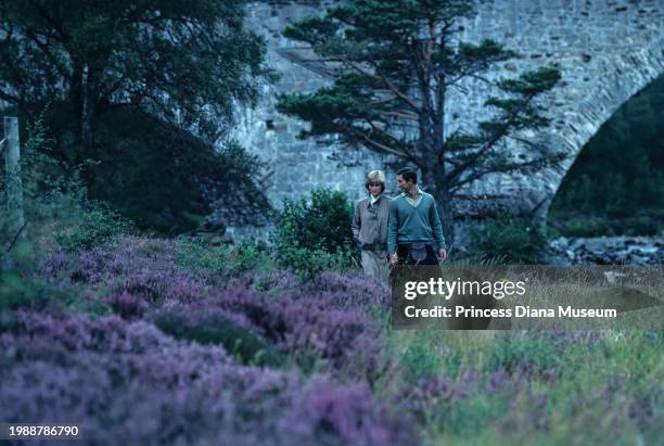 Diana, Princess of Wales , wearing a suit designed by Bill Pashley, and husband Charles III of the United Kingdom walk along the banks of the river...