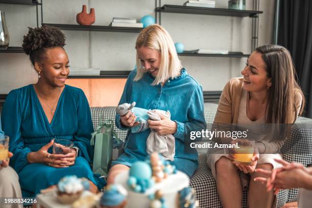 baby shower fun: friends giving gifts and share laughter with expectant mom - presents 20 years of giving stock pictures, royalty-free photos & images