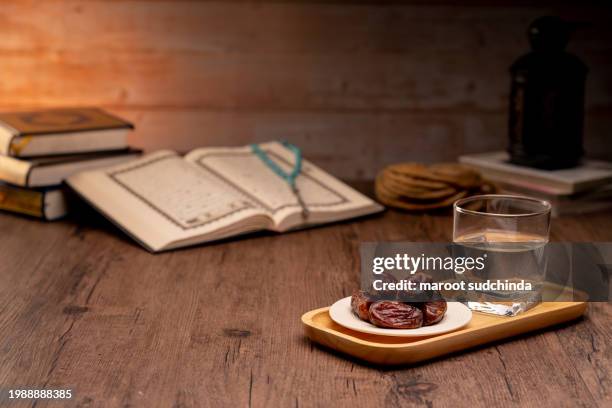 ramadan muslims, many date palms are on bowls, plates, and cups of water, and the quran is on wooden tables - arabic calligraphy stock pictures, royalty-free photos & images