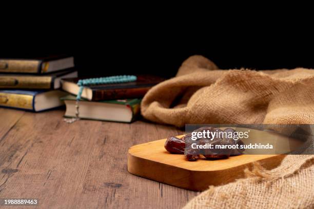 ramadan muslims, many date palms are on bowls, plates, and cups of water, and the quran is on wooden tables - arabic calligraphy stock pictures, royalty-free photos & images