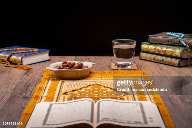 ramadan muslims, many date palms are on bowls, plates, and cups of water, and the quran is on wooden tables - arabic calligraphy stock pictures, royalty-free photos & images
