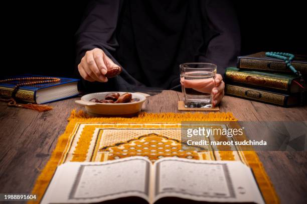 ramadan muslims, many date palms are on bowls, plates, and cups of water, and the quran is on wooden tables - arabic calligraphy stock pictures, royalty-free photos & images