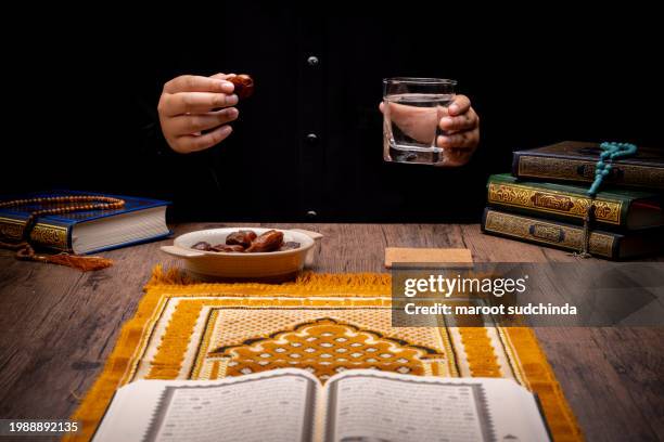 ramadan muslims, many date palms are on bowls, plates, and cups of water, and the quran is on wooden tables - arabic calligraphy stock pictures, royalty-free photos & images