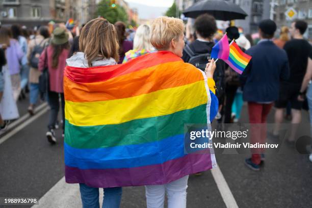 a lgbtqi couple wearing flags during pride event - pride stock pictures, royalty-free photos & images