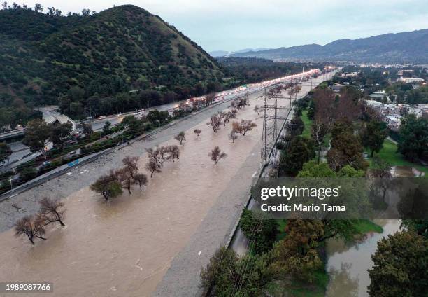 An aerial view of the Los Angeles River swollen by storm runoff as a powerful long-duration atmospheric river storm, the second in less than a week,...