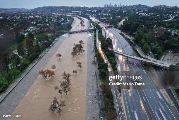 An aerial view of the Los Angeles River swollen by storm runoff as a powerful long-duration atmospheric river storm, the second in less than a week,...