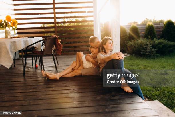 relaxed family sitting on patio at sunset - avondschemering stockfoto's en -beelden