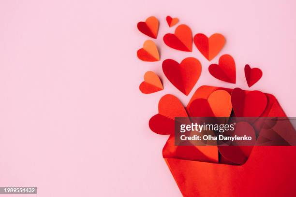 red envelope with paper hearts on pink background. valentines day, love concept - hearth day fotografías e imágenes de stock