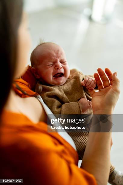 nouveau-né pleurant dans les mains de sa mère - larme photos et images de collection