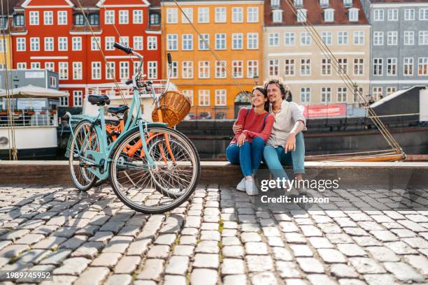 young couple relaxing in nyhavn canal in copenhagen in denmark - copenhagen nyhavn stock pictures, royalty-free photos & images