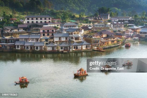 traditional chinese-style boats on misty river lake at dawn, sunrise against mountain hills of baan rak thai, mae hong son, thailand - mae hong son province stock pictures, royalty-free photos & images