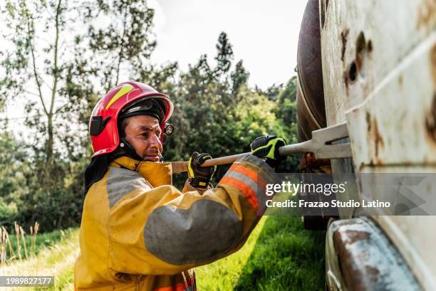 feuerwehrmann mit einem brecheisen, um bei einem unfall eine fahrzeugtür aufzubrechen - brecheisen stock-fotos und bilder