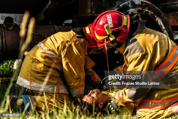 firefighters helping a car accident victim - victim services stock pictures, royalty-free photos & images