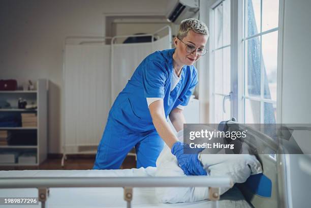nurse making bed at the hospital - housekeeping uniform stock pictures, royalty-free photos & images