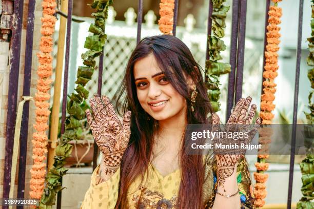 an indian woman posing while showing off the henna (mehndi) applied on her hands. - festival wristband stock pictures, royalty-free photos & images
