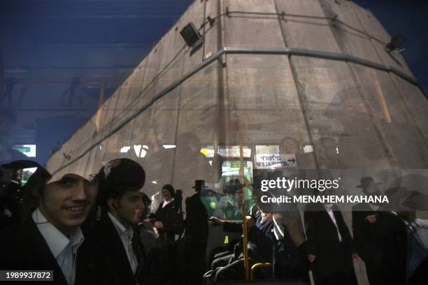 Ultra orthodox Jews are reflected on a bus window near a concrete wall protecting Rachel's Tomb, Judaism's third holiest shrine, located in the West...