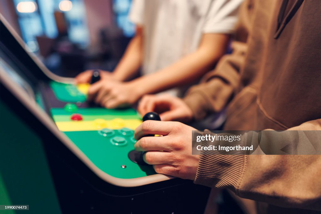 Closeup of teenagers playing retro arcade video game