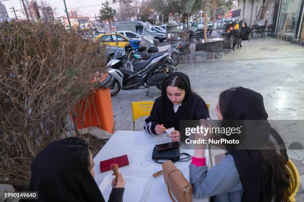 Young Iranian women are eating ice cream while sitting together at an outdoor ice cream cafe in the holy city of Qom, 145 km south of Tehran, at...
