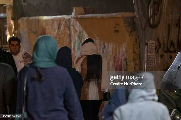 Young Iranian women are walking along a street in Qom, Iran, 145 km south of Tehran, at night on February 8, 2024. Qom is known as the religious...