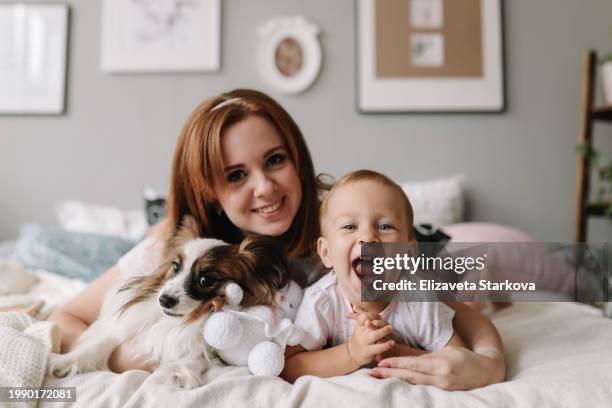 beautiful young mother and little daughter having fun in bed in bedroom at home - human body part stock pictures, royalty-free photos & images