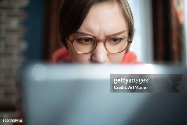 concerned, sad, tired and worried young woman with laptop at home reading some bad news or having problems or fraud - scam victim stock pictures, royalty-free photos & images