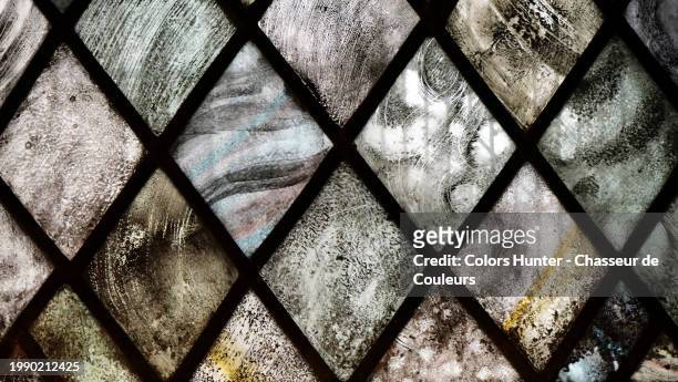 close up of a gray, brown and pink toned stained glass window with a diamond pattern in london, england, united kingdom. sunlight. natural colors. - basilican church stock pictures, royalty-free photos & images
