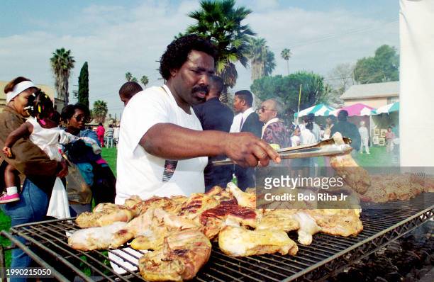 Chef Denton Hudson monitors chicken on the grill as he participates in Martin Luther King Parade and celebration along Jefferson Blvd, January 30,...