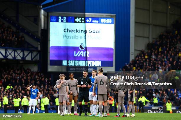 Players from both sides wait alongside referee Michael Oliver for a VAR decision on Everton's second goal during the Premier League match between...