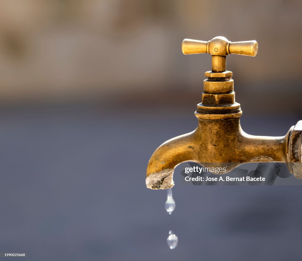 Outdoor drinking water faucet with dripping water drops.