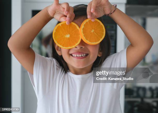 unfug kleines mädchen, das mit orangenscheibe spielt - gesicht verstecken stock-fotos und bilder