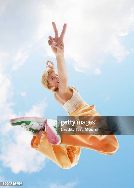 woman posing making peace sign - women mid air stock pictures, royalty-free photos & images