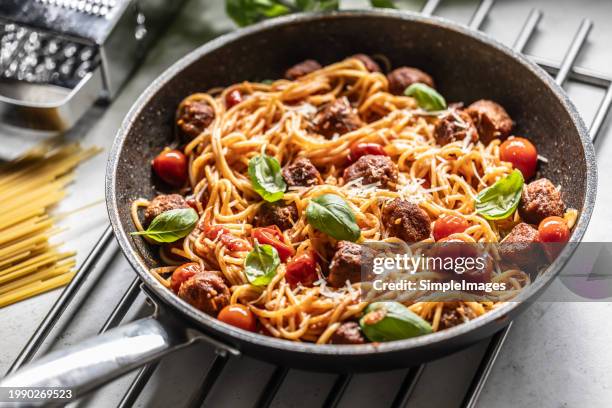 meatballs with spaghettis tomato sauce in a pan. italian pasta with beef balls in tomato sauce, parmesan and basil. - pasta italiana fotografías e imágenes de stock