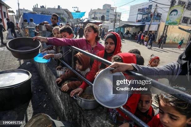 Palestinians children wait in line to receive food prepared by volunteers for Palestinian families ,displaced to Southern Gaza due to Israeli...