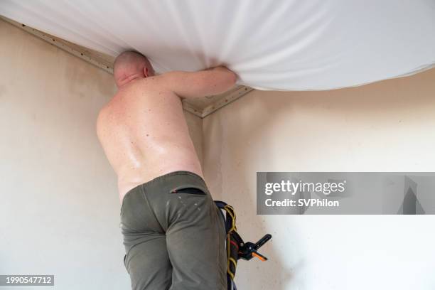 the worker stretches the suspended ceiling. - stretch ceiling stock pictures, royalty-free photos & images