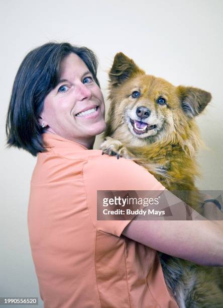Woman with short hair holding her crossbreed dog, with love and affection, 2011. .