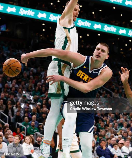 Nikola Jokic of the Denver Nuggets passes around Kristaps Porzingis of the Boston Celtics during the first quarter at TD Garden on January 19, 2024...