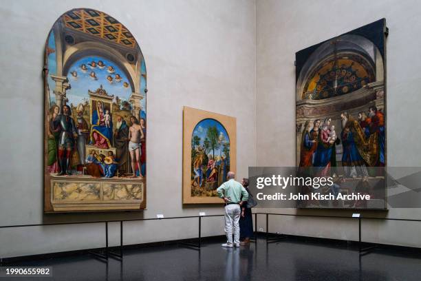 Pair of museum goers look at Cima da Conegliano's 'Madonna of the Orange Tree' at the Gallerie dell'Accademia, Venice, Italy, 2010. On either side of...