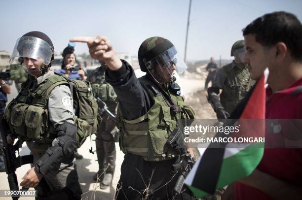 An Israeli border policeman gestures towards Palestinian protestors during a weekly demonstration in the West Bank village of Nabi Saleh on September...